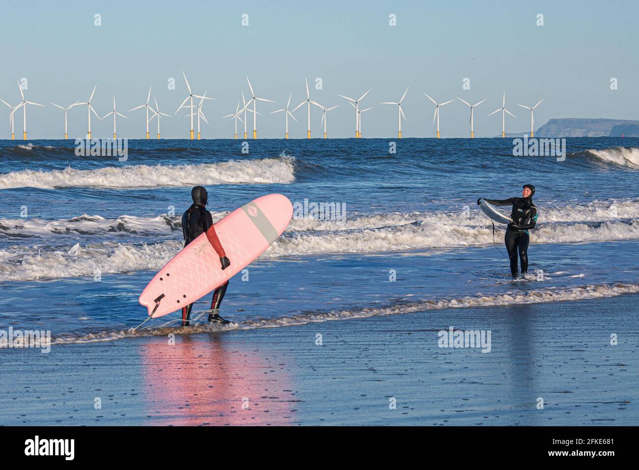 Olivia Harris (a destra) e il suo amico Rachel surf a Seaton con in distanza. Inghilterra, Regno Unito Foto Stock