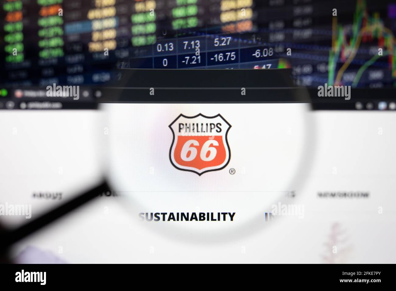 Phillips 66 logo aziendale su un sito web con sviluppi sfocati del mercato azionario in background, visto su uno schermo del computer attraverso una lente di ingrandimento Foto Stock