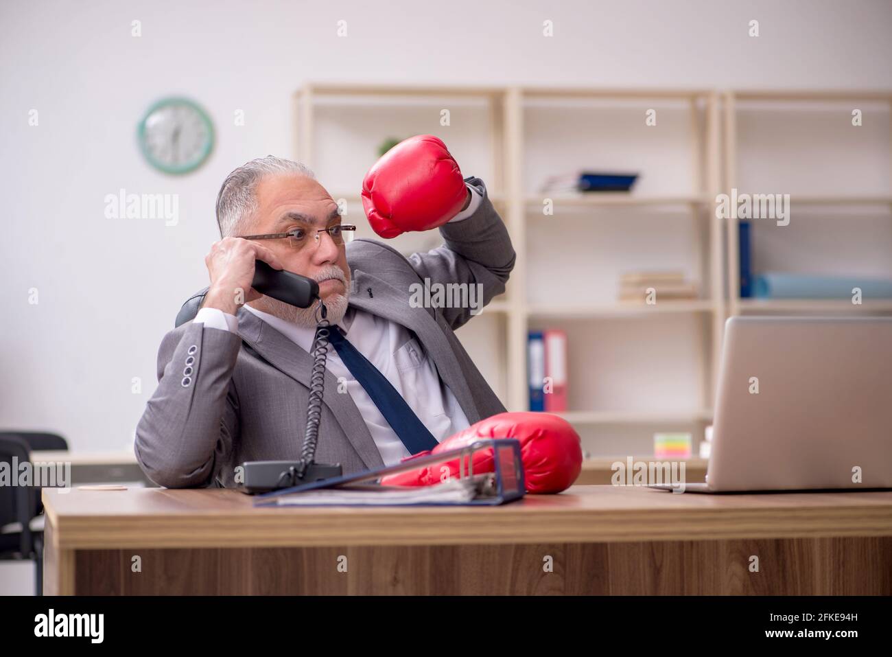 Vecchio dipendente di sesso maschile che indossa guanti da boxe in ufficio  Foto stock - Alamy