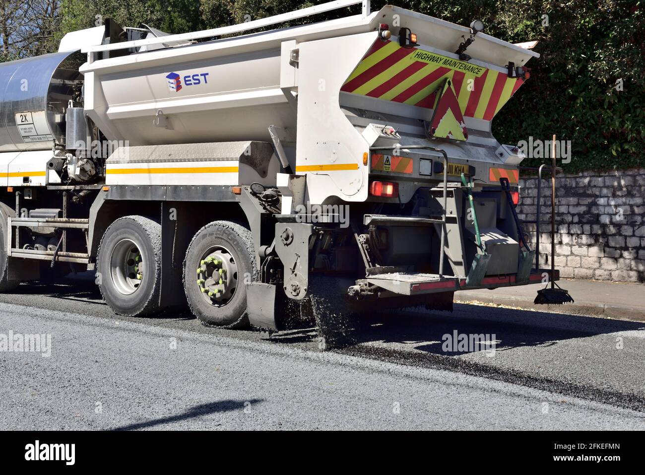 Manutenzione stradale spandimento di trucioli di bitume e ghiaia per la rettifica Foto Stock