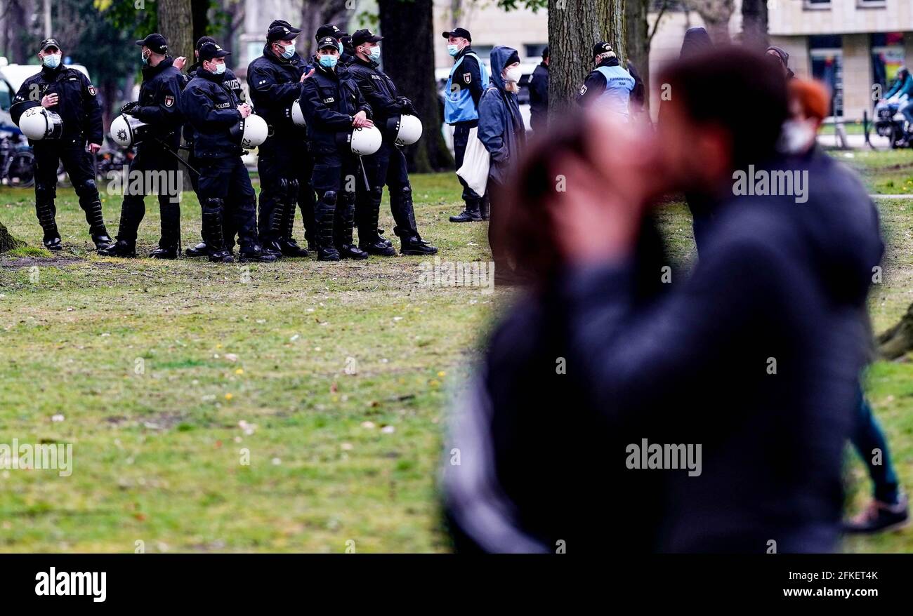 Amburgo, Germania. 01 Maggio 2021. Un uomo e una donna baciano di fronte a un gruppo di poliziotti che controllano un parco vicino alla stazione ferroviaria Dammtor di Amburgo. Per il giorno di maggio, i gruppi di sinistra e di estrema sinistra hanno annunciato numerosi incontri e processioni durante tutto il giorno, soprattutto nella zona del centro della città e dei quartieri adiacenti. Credit: Axel Heimken/dpa/Alamy Live News Foto Stock