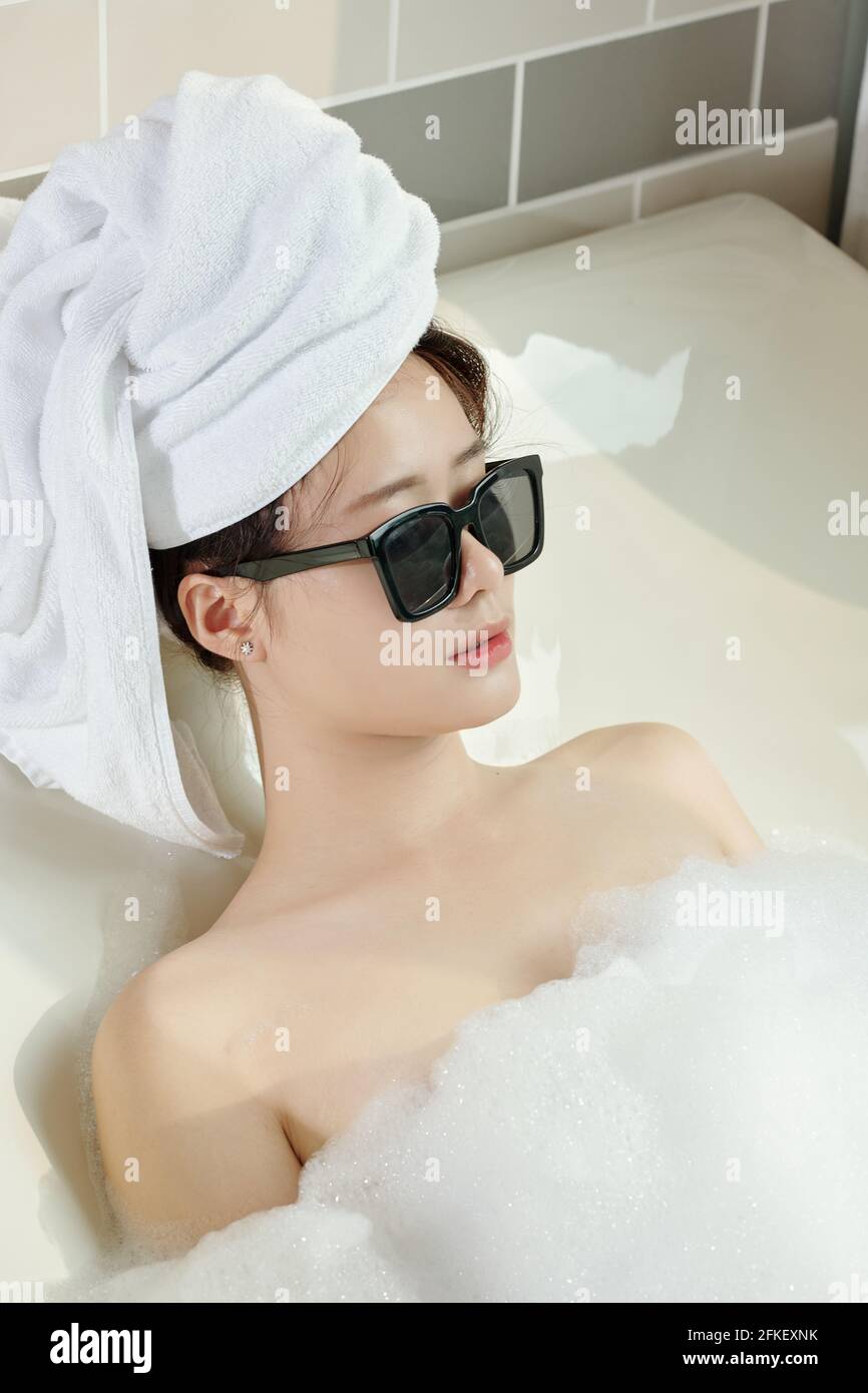 Splendida giovane donna in occhiali da sole e asciugamano sulla testa rilassante in vasca da bagno con schiuma perfetto concetto di sera Foto stock Alamy