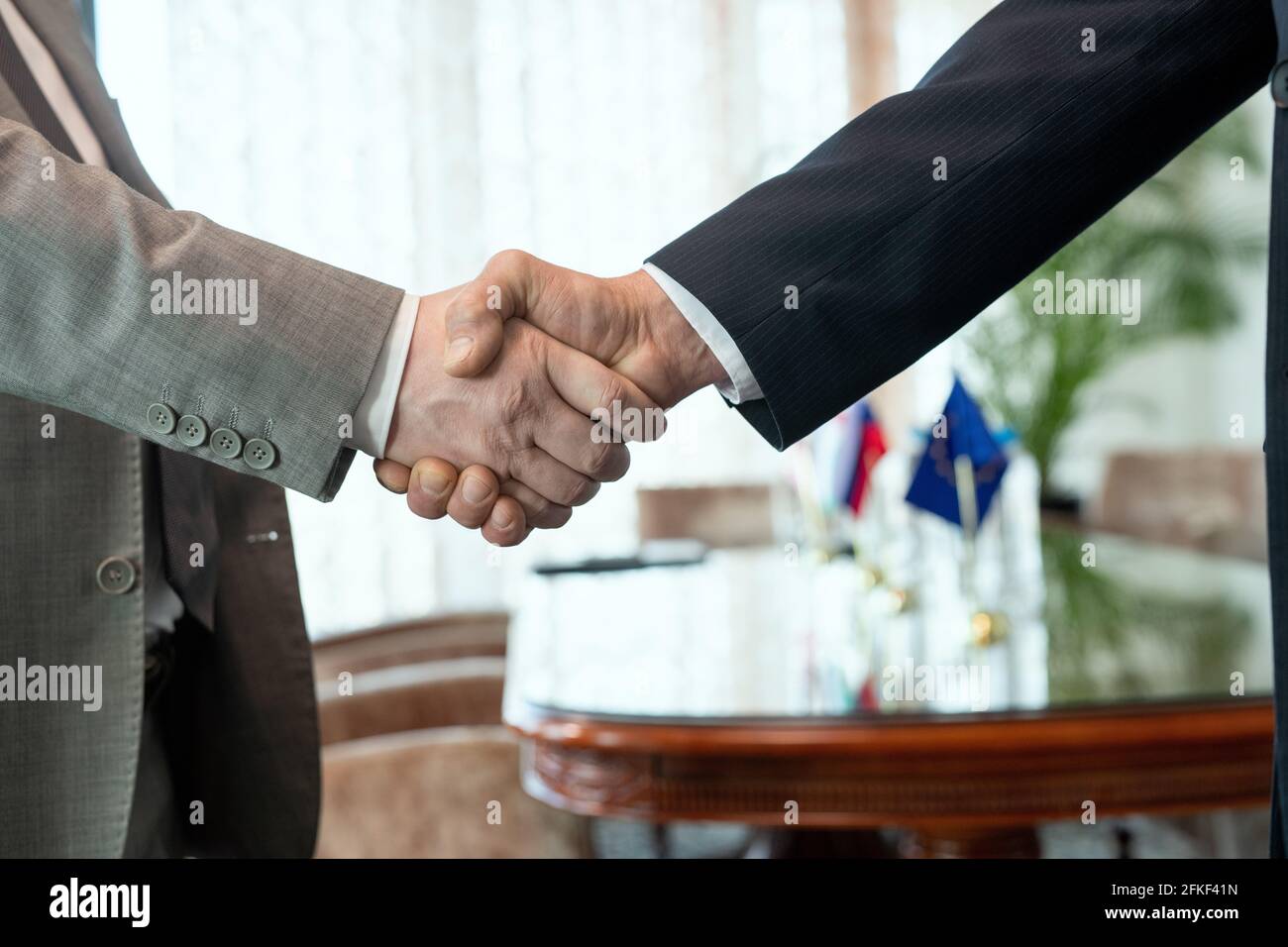 Due uomini d'affari scuotono le mani dopo aver fatto l'affare in ufficio Foto Stock