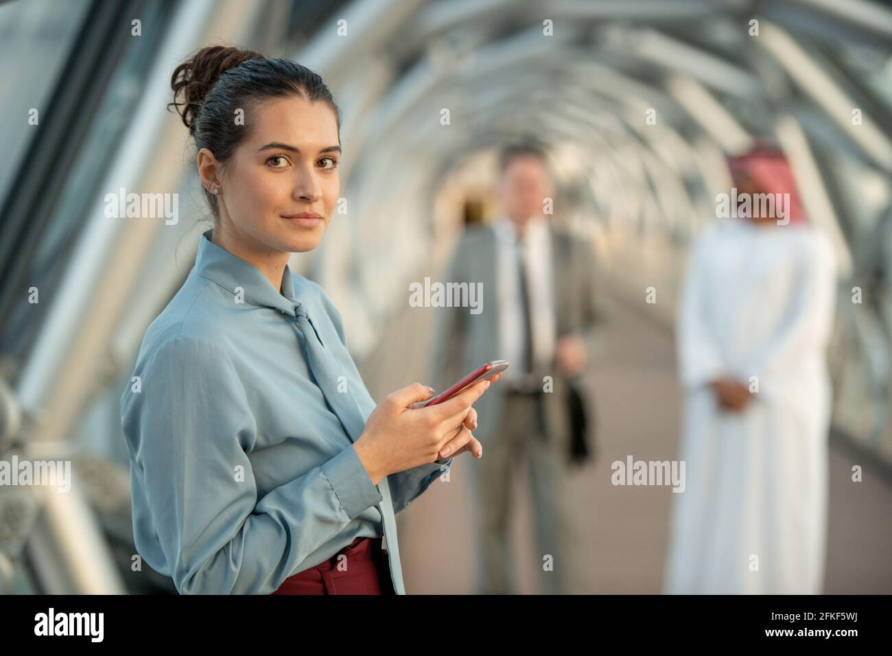 Giovane donna d'affari che guarda giovani mentre usa il telefono cellulare Foto Stock