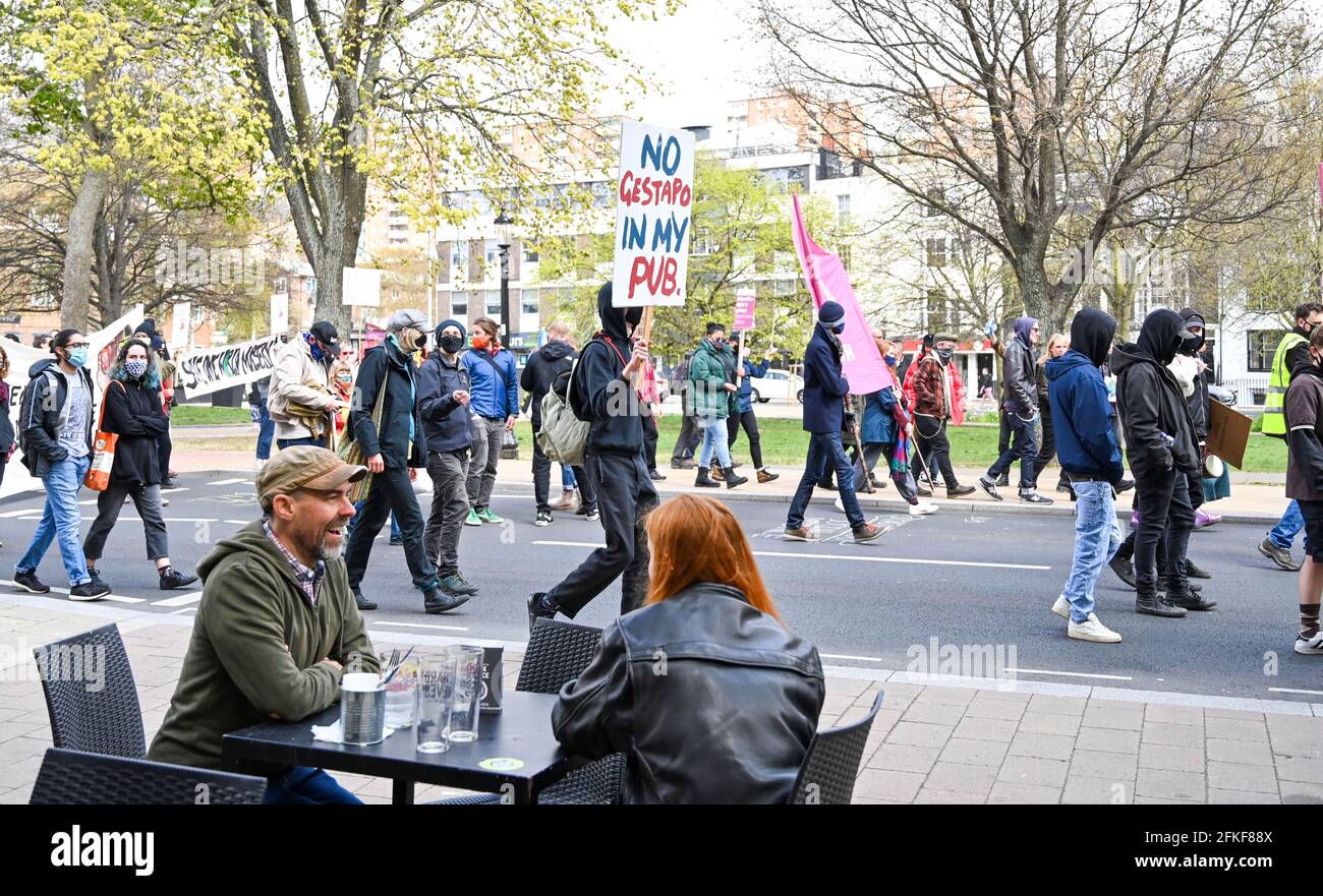 Brighton UK 1 maggio 2021 - centinaia di Kill i manifestanti di Bill passano dai bevitori fuori da un pub a Brighton mentre si dirigono oggi attraverso Brighton in occasione della Giornata Internazionale dei lavoratori, come dimostrano contro il nuovo governo di polizia, crimine, condanna e giustizia legge. Dimostrazioni si svolgono in tutto il paese in quello che è anche noto come Labor Day: Credit Simon Dack / Alamy Live News Foto Stock