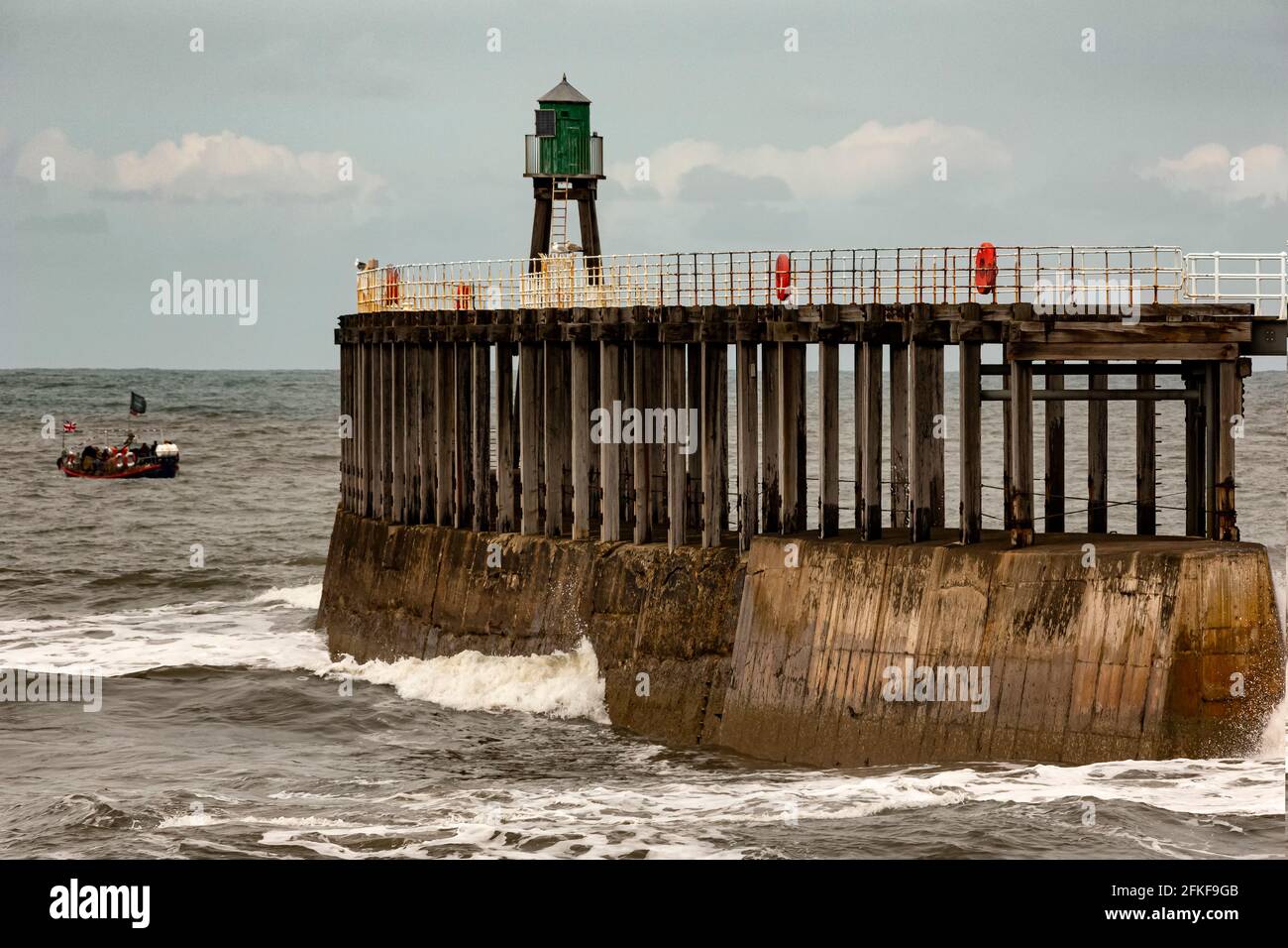 Una giornata molto ventosa sul molo Whitby, nello Yorkshire del Nord, Inghilterra. Whitby è una città storica con le sue strade stravaganti, i negozi e le rovine dell'abbazia. Foto Stock