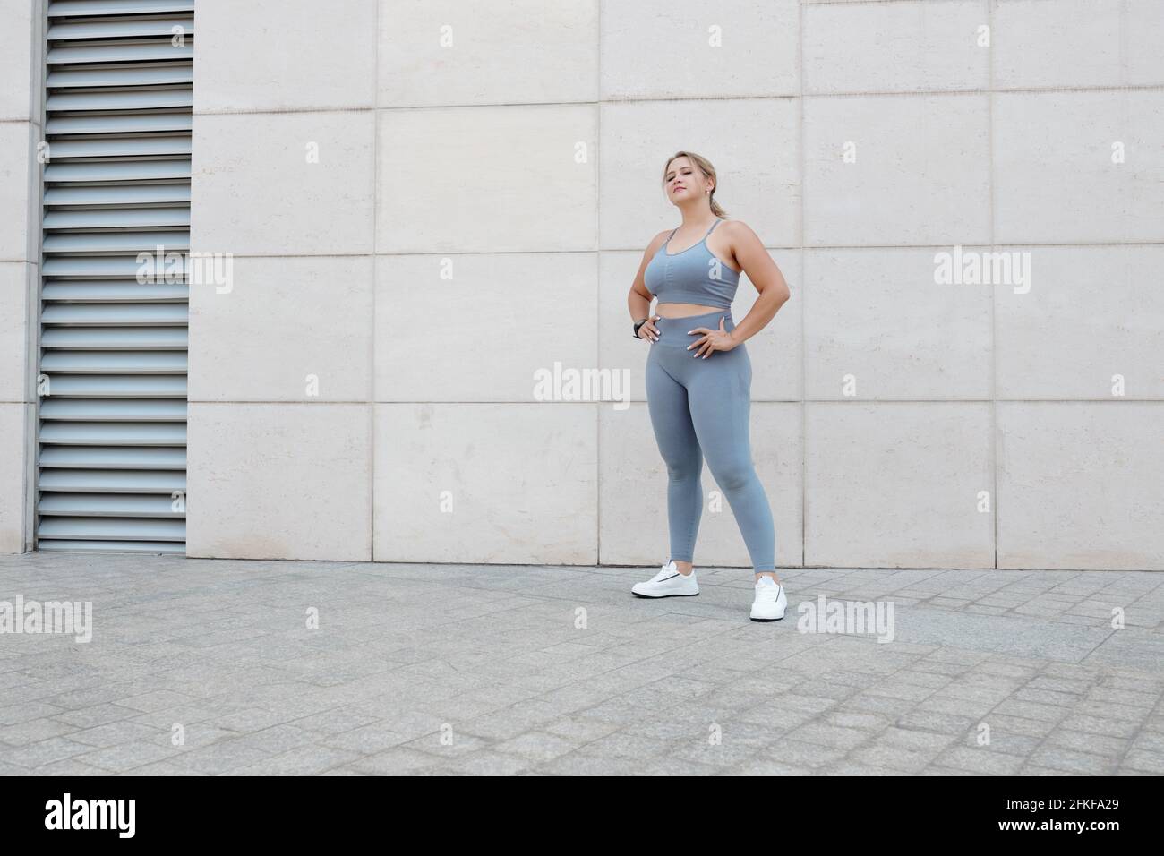 Bella misura giovane più donna taglia in reggiseno sportivo e. leggings che si levano in piedi all'aperto dopo il jogging Foto Stock
