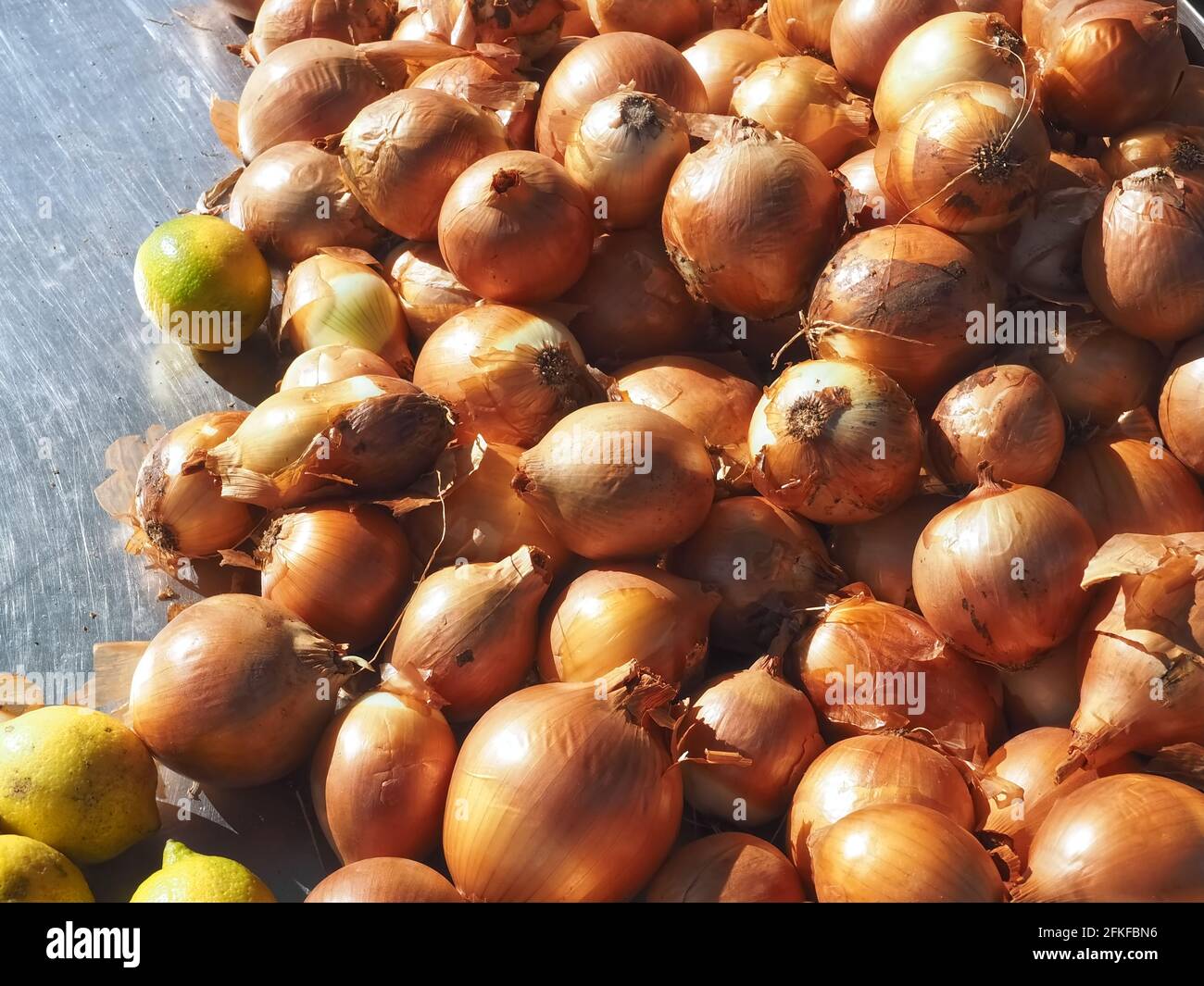 Macro di un mucchio di cipolle intere e limoni a. un mercato Foto Stock