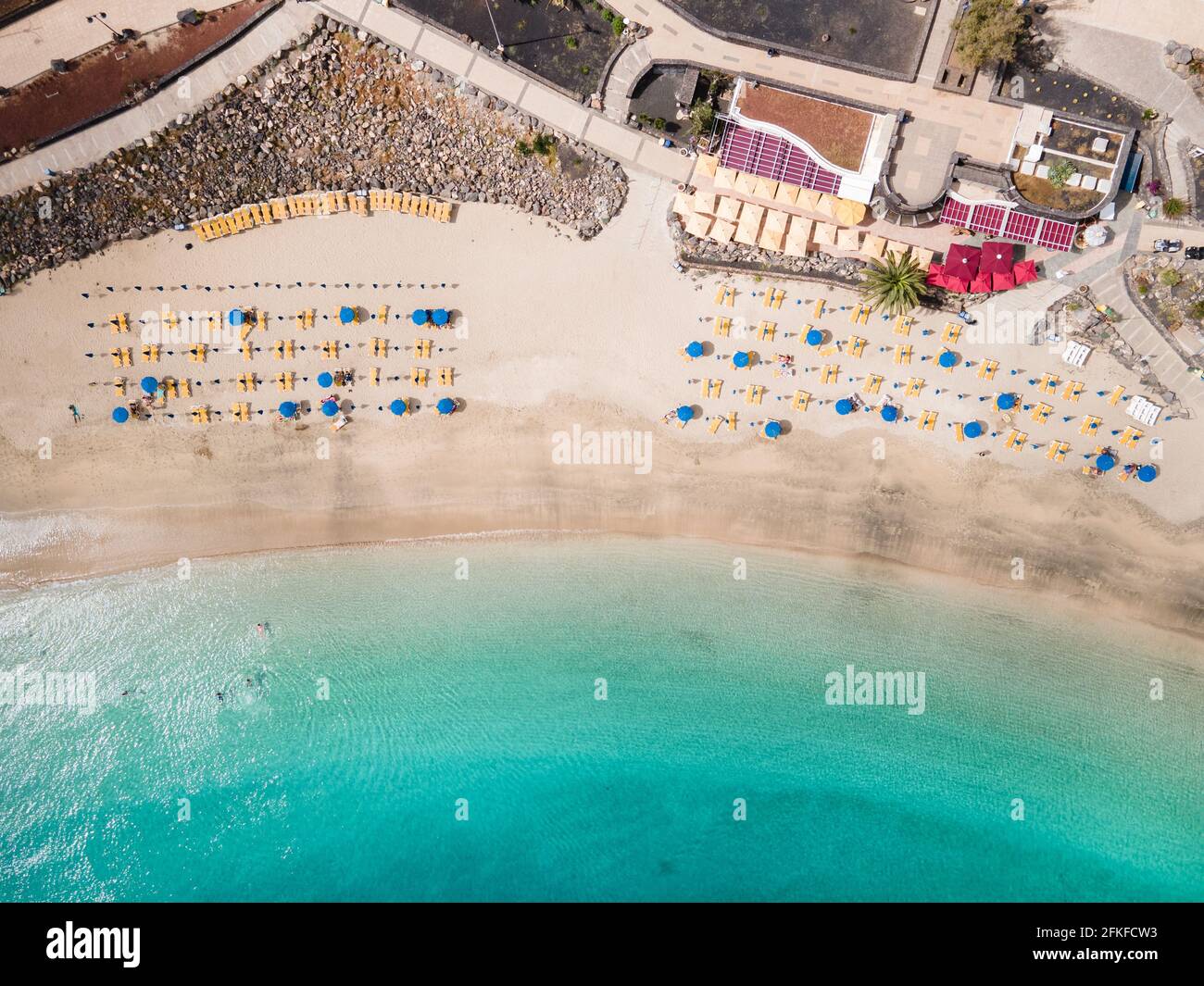 Spiaggia di sabbia bianca con persone, ombrelloni e lettini vista dall'alto Foto Stock