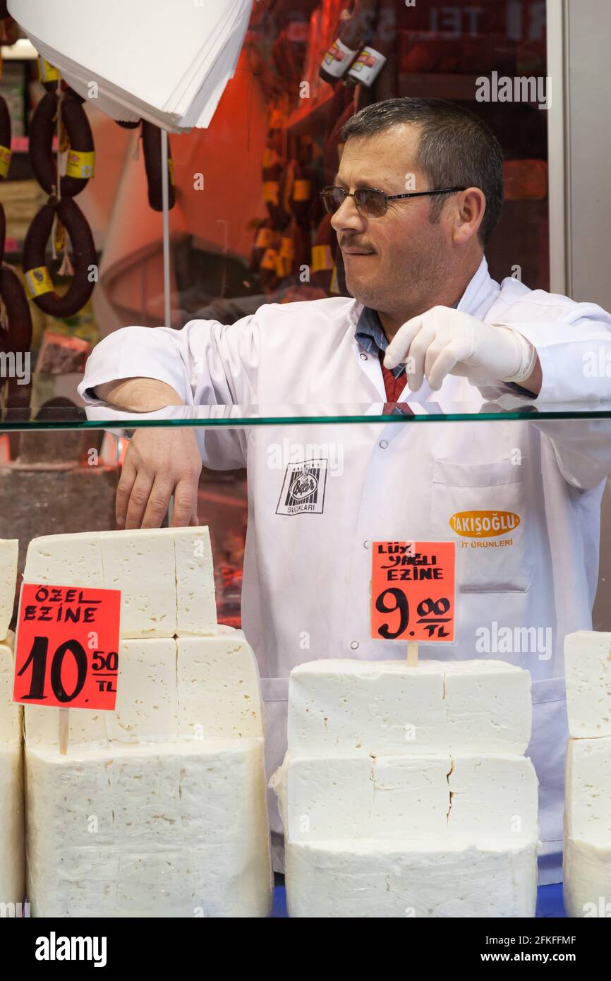 Venditore nel mercato di Istanbul con grandi blocchi di formaggio Foto Stock