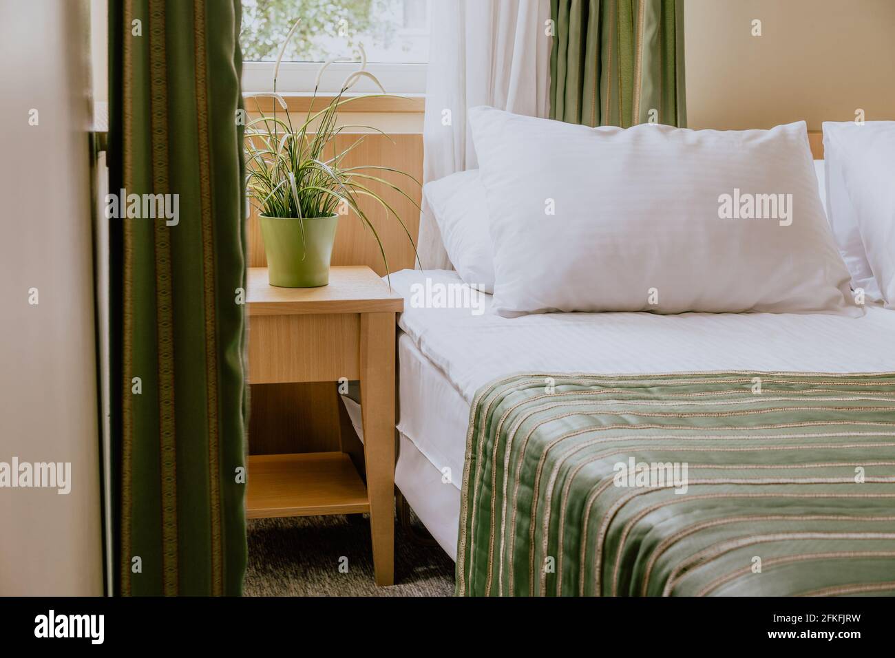 Piccola camera d'albergo con un letto matrimoniale e un comodino tavolo  sotto la finestra decorato con una pianta Foto stock - Alamy