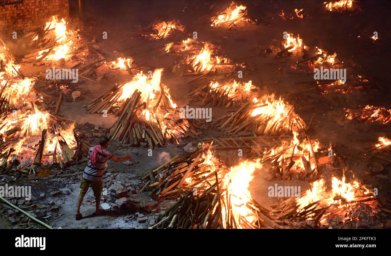 Nuova Delhi, India. 01 Maggio 2021. I lavoratori e i membri della famiglia portano un corpo per la cremazione vicino a più pire funerarie delle vittime di COVID-19 bruciare su un terreno che è stato convertito in un crematorio per la cremazione di massa a Nuova Delhi, India il Sabato, 1 maggio 2021. Foto di Abhishek/UPI Credit: UPI/Alamy Live News Foto Stock