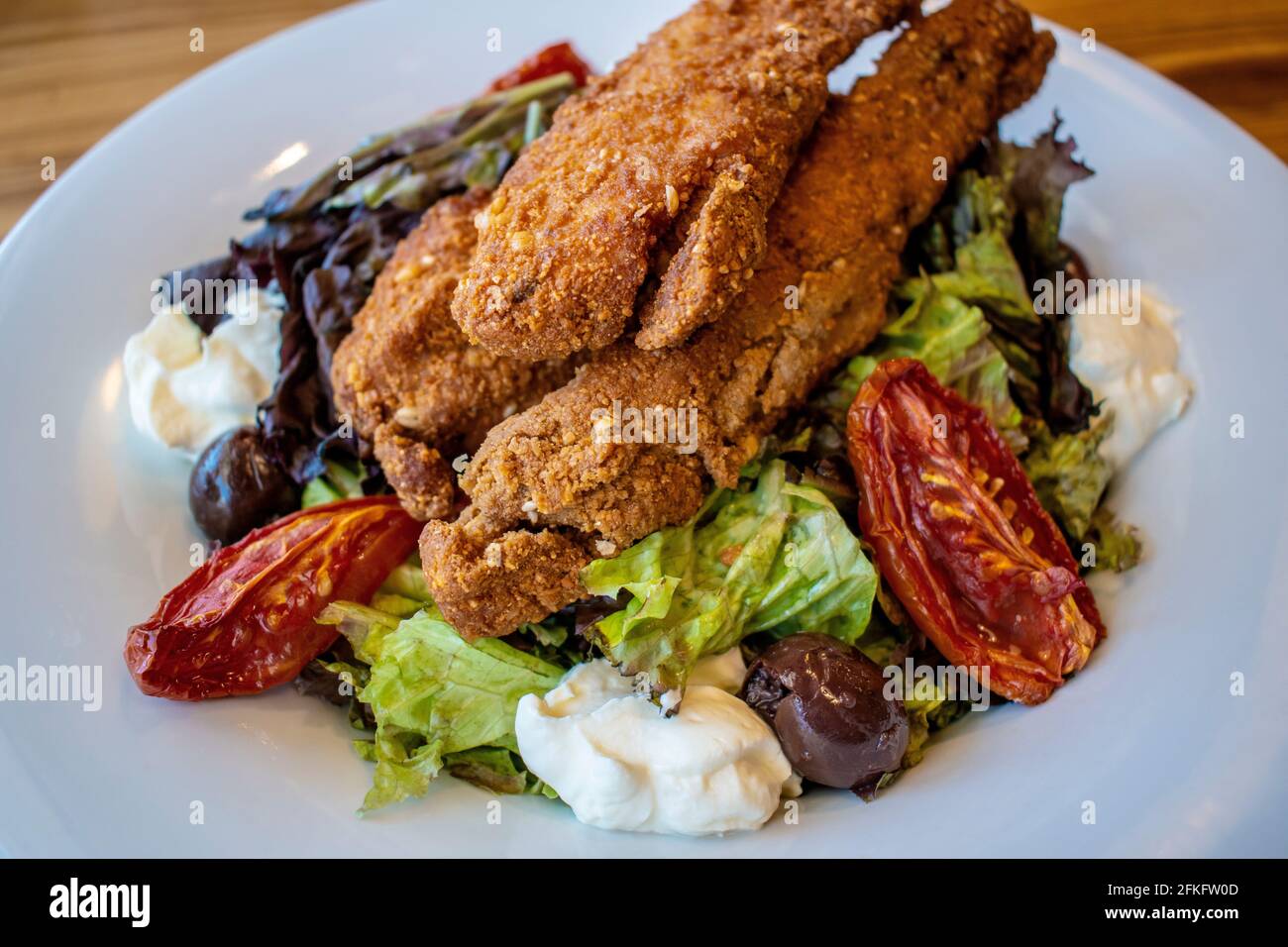 Insalata croccante di pollo (foglie verdi, pollo fritto, formaggio finlandese, pomodori canditi e olive nere). Foto Stock