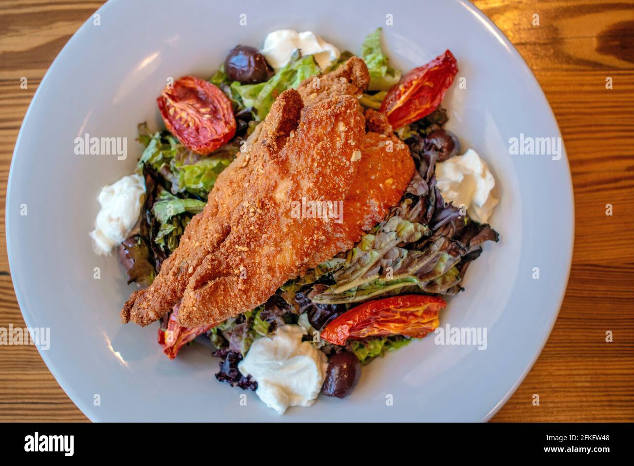 Insalata croccante di pollo (foglie verdi, pollo fritto, formaggio finlandese, pomodori canditi e olive nere). Foto Stock