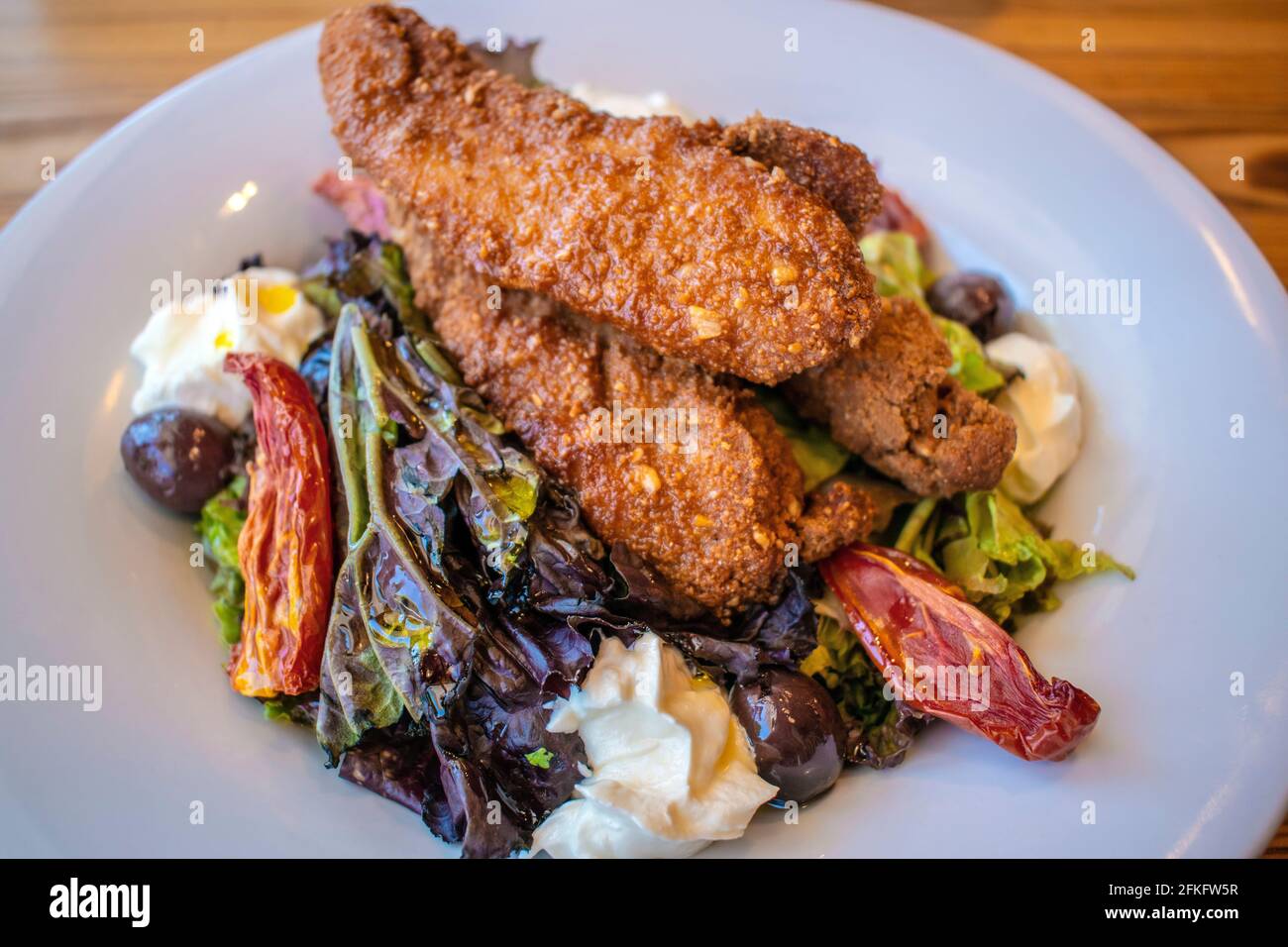 Insalata croccante di pollo (foglie verdi, pollo fritto, formaggio finlandese, pomodori canditi e olive nere). Foto Stock