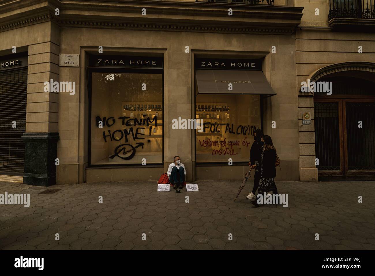 Barcellona, Spagna. 1 maggio 2021. Un uomo senza casa si siede di fronte a  un negozio 'ZARA HOME' dopo che gli attivisti hanno dipinto 'non abbiamo  una casa' sulla finestra durante una