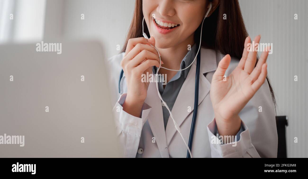 Il medico asiatico della donna è in linea che visita con un paziente sopra L'applicazione Internet e l'ascolto dei sintomi e spiega come trattare il d iniziale Foto Stock