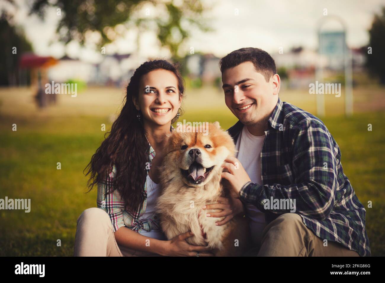 Giovane coppia felice che gioca con un cane chow Foto Stock