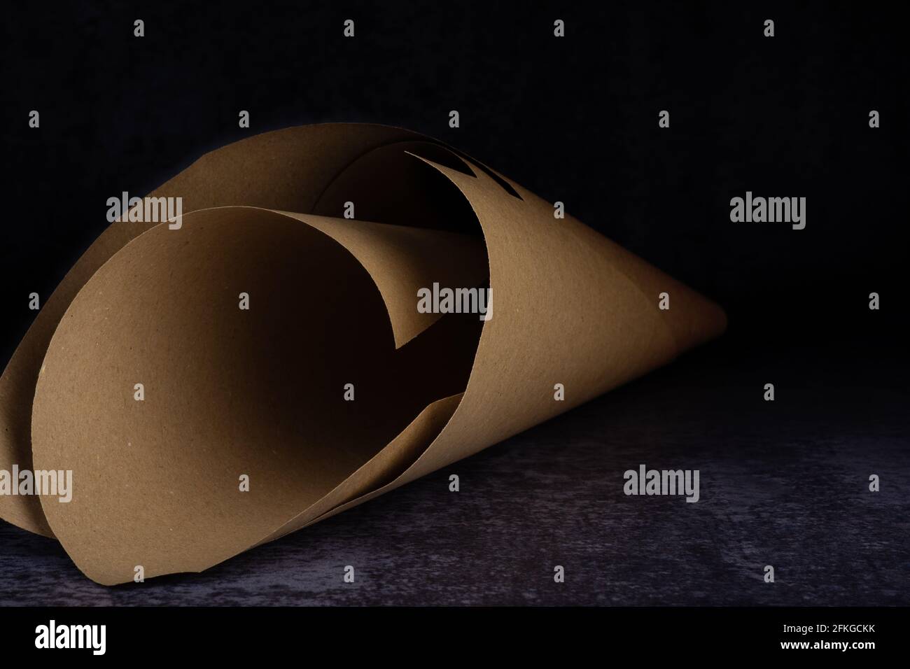 Un cono di carta su un blu chiaro e scuro sporco sfondo Foto Stock