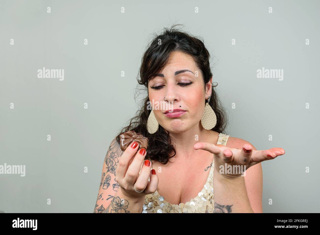 Donna tatuata con un volto di rammarico per aver mangiato torta al miele brasiliana. Foto Stock