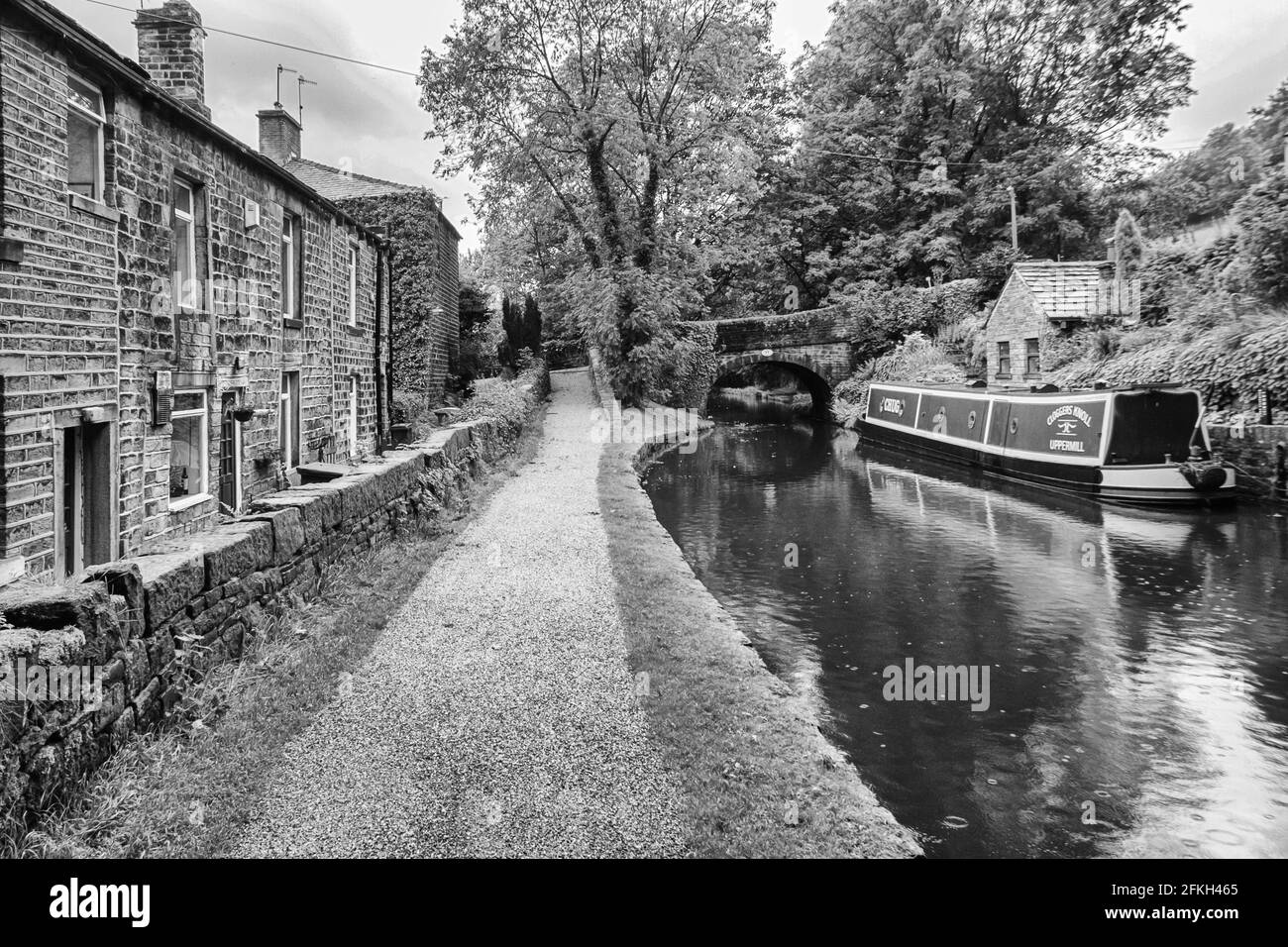 Chiatta ormeggiata sul canale stretto di Huddersfield da cottage, Greenfield, Oldham Foto Stock