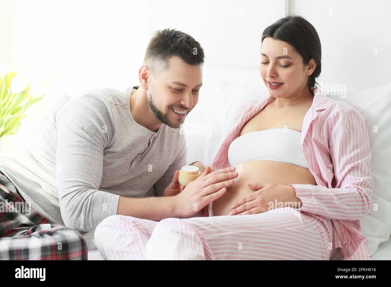 Bella coppia incinta con crema a casa Foto Stock