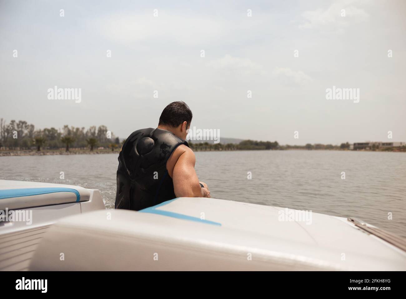 Uomo ispanico seduto, calmo, in una barca sul lago a mezzogiorno Foto Stock