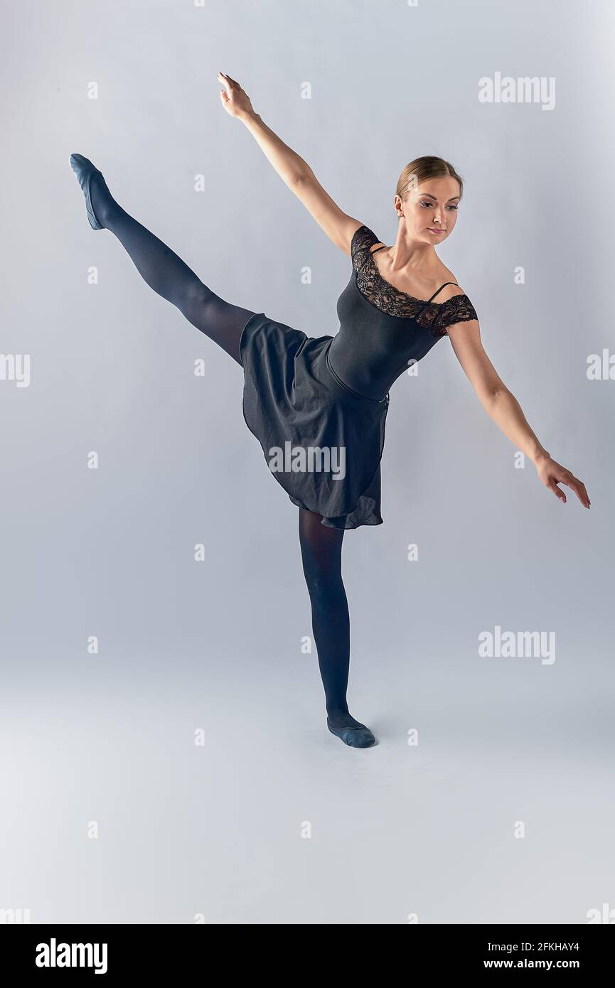 La ballerina è in piedi sullo sfondo e si è sollevata la gamba in su appoggiandosi verso il pavimento Foto Stock