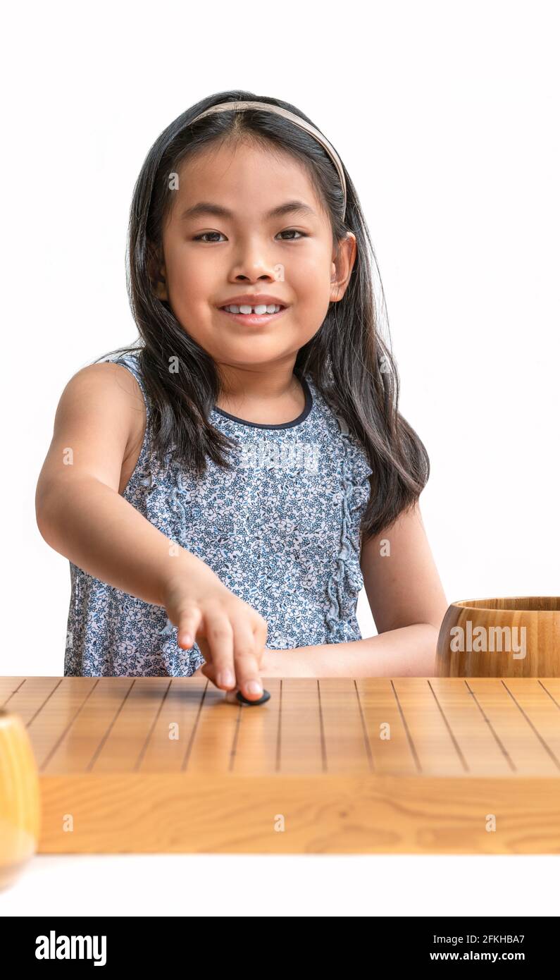Ritratto carino ragazza asiatica bambino giocare Go o il gioco di scacchi giapponese o scacchi cinese gioco da tavolo, guardando la fotocamera e sorriso, sfondo bianco, Foto Stock