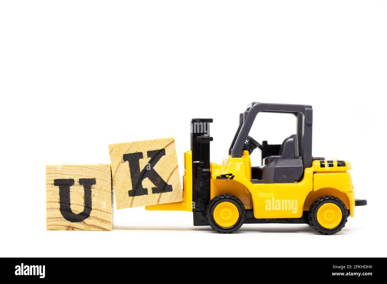 Carrello elevatore giocattolo tenere il blocco di lettera k per completare la parola UK (abbreviazione del regno unito) su sfondo di legno Foto Stock