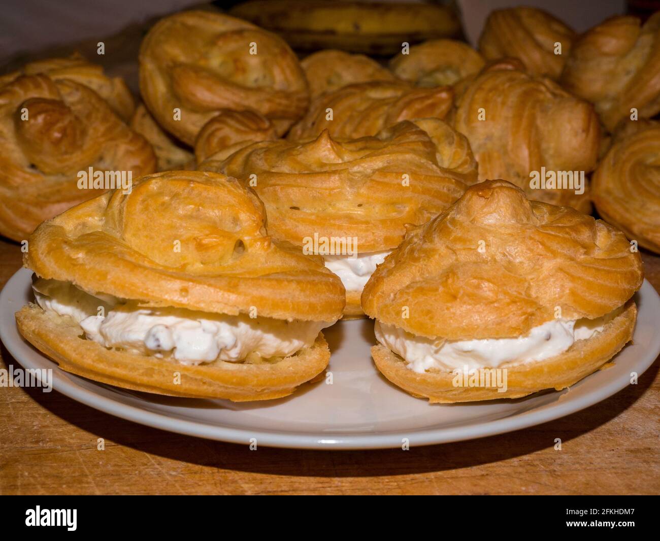 Profiterolo o crema di panna ripiena con panna montata un bianco piastra Foto Stock