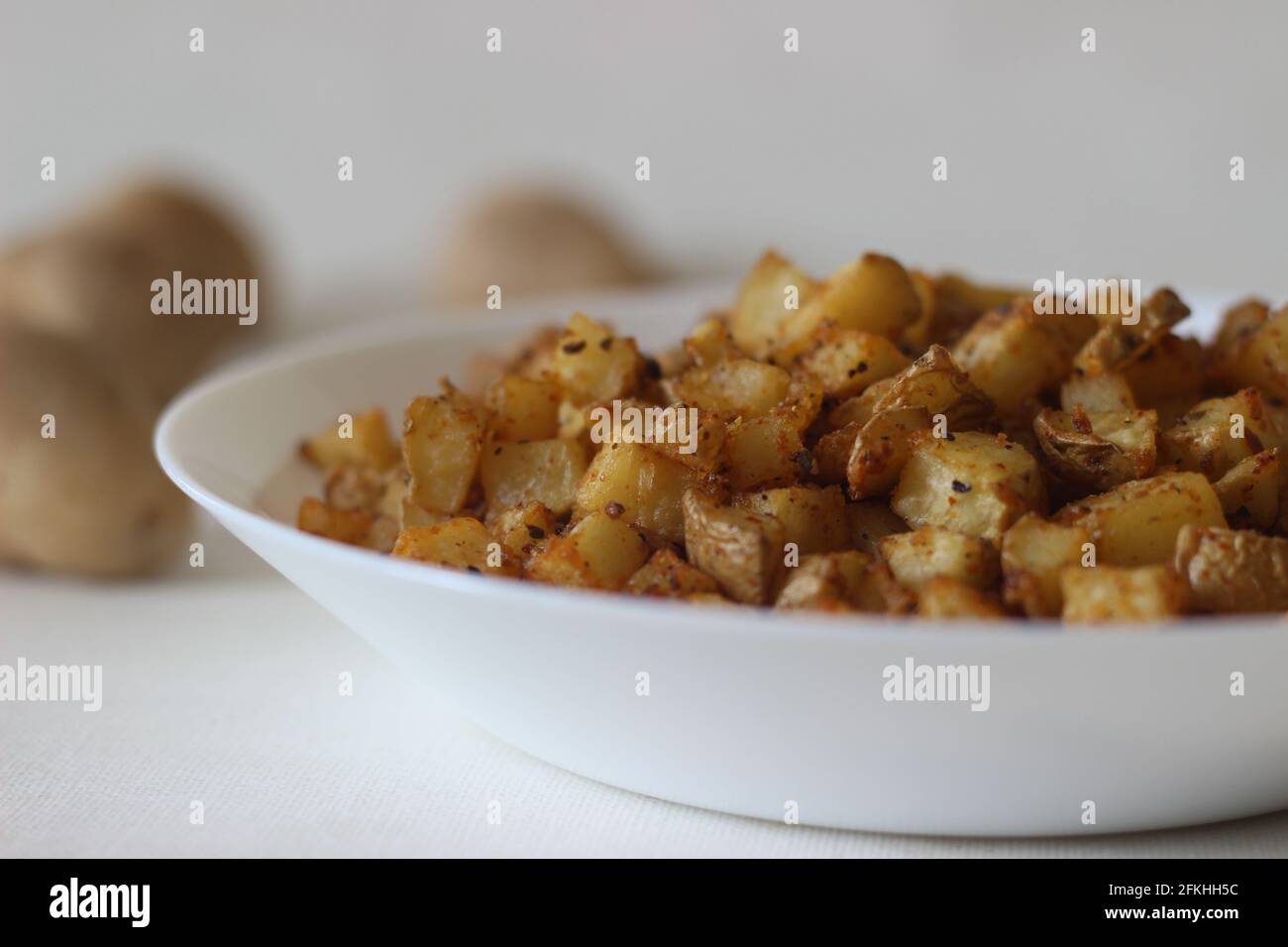 Patate a cubetti arrostite in friggitrice ad aria. Scatto su sfondo bianco. Foto Stock