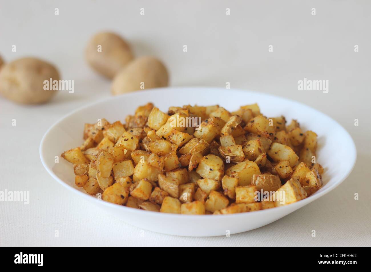 Patate a cubetti arrostite in friggitrice ad aria. Scatto su sfondo bianco. Foto Stock