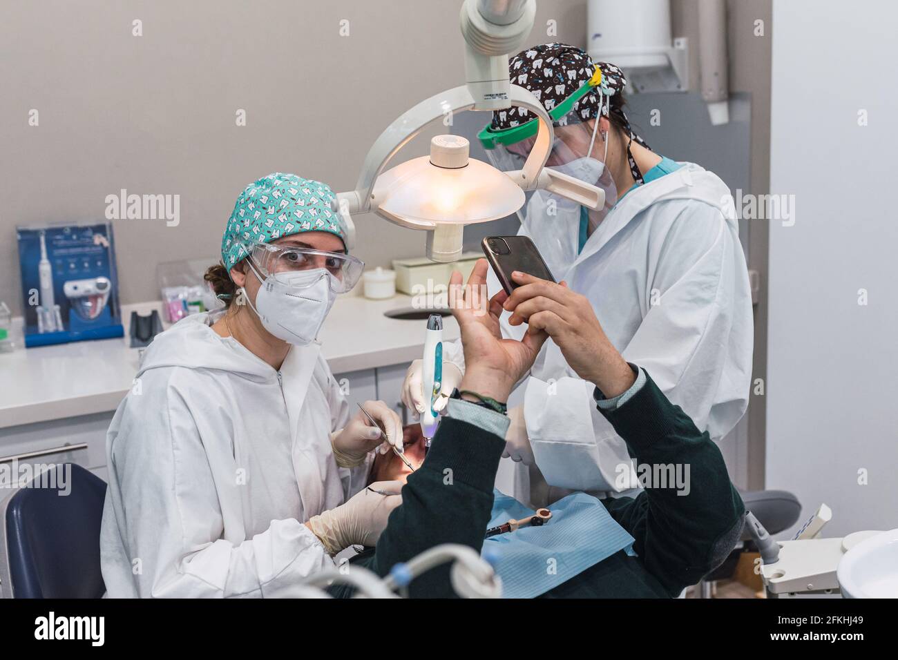 Paziente che prende un selfie nello studio dentistico. Tre persone. Medico femminile. Concetto di accoglienza e benessere. Sorrisi Foto Stock