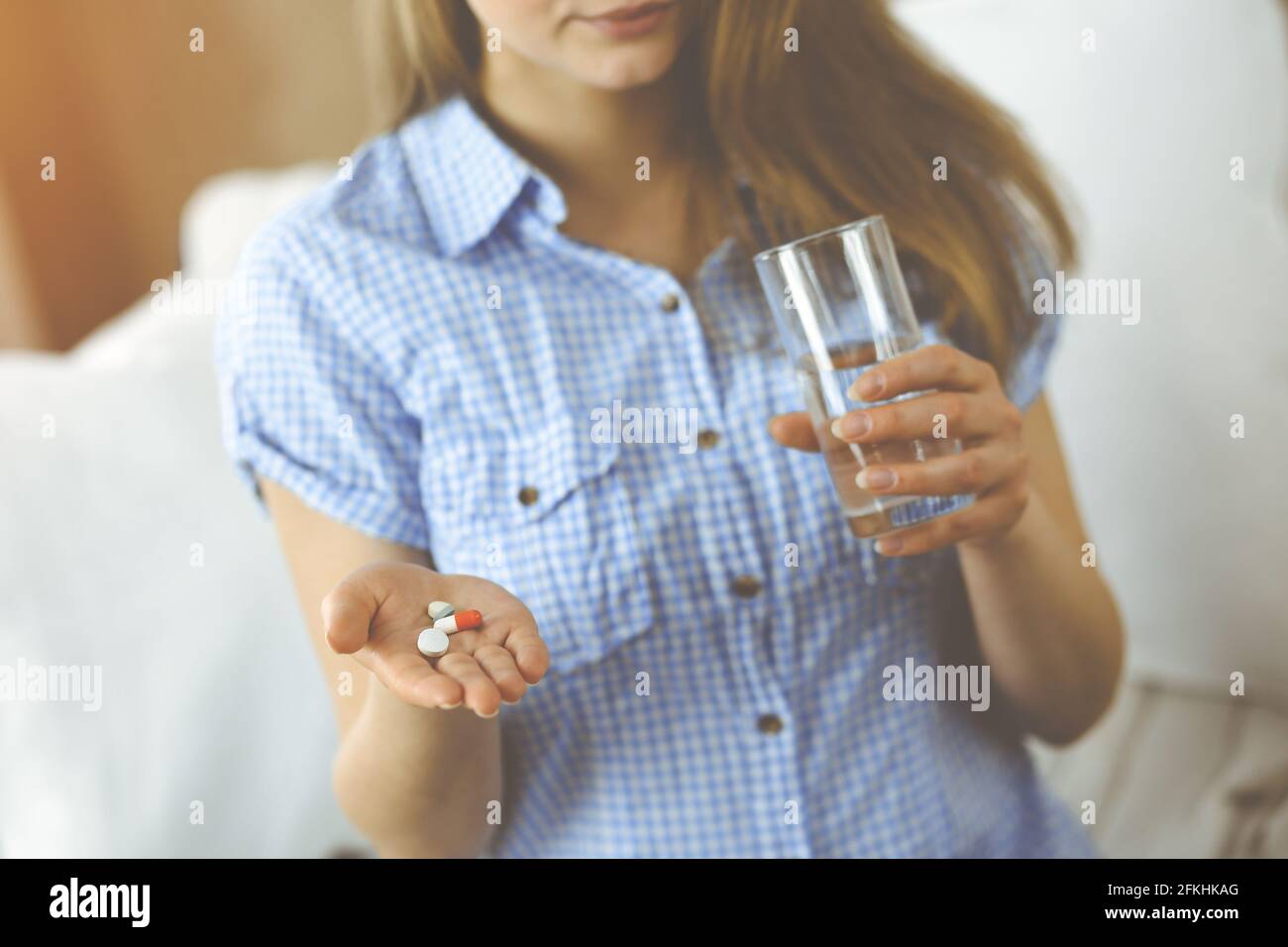 Close-up donna che tiene pillole tempo di prendere farmaci, cura per mal di testa. Concetto di medicina durante l'autoisolamento e pandemia di Coronavirus Foto Stock