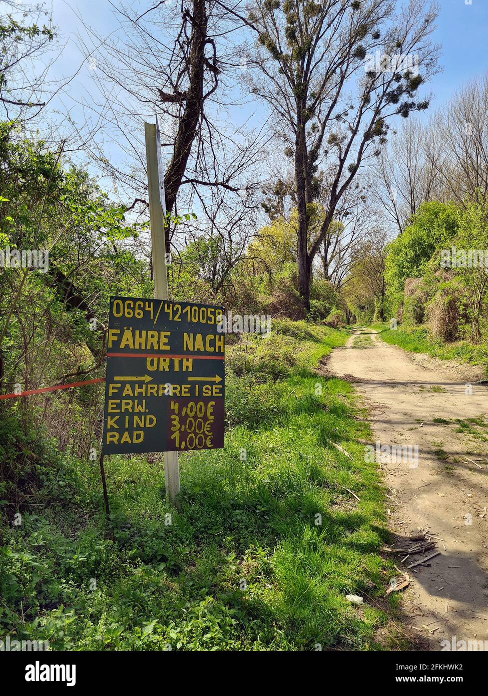 Haslau, Austria - 24 aprile 2021: Sentiero escursionistico attraverso le zone umide e cartelli per il traghetto passeggeri attraverso il Danubio al villaggio Orth an de Foto Stock