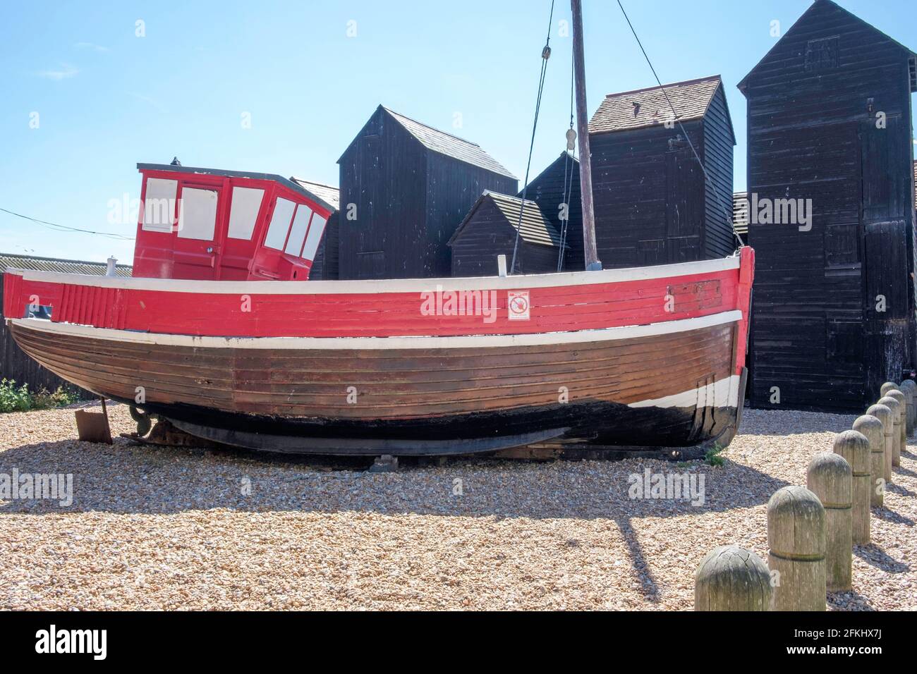 Idea di staycation. Vecchia barca di legno da pesca in camicia allo Stade, Hastings, East Sussex, con Net Shops in background. Inghilterra, Regno Unito Foto Stock
