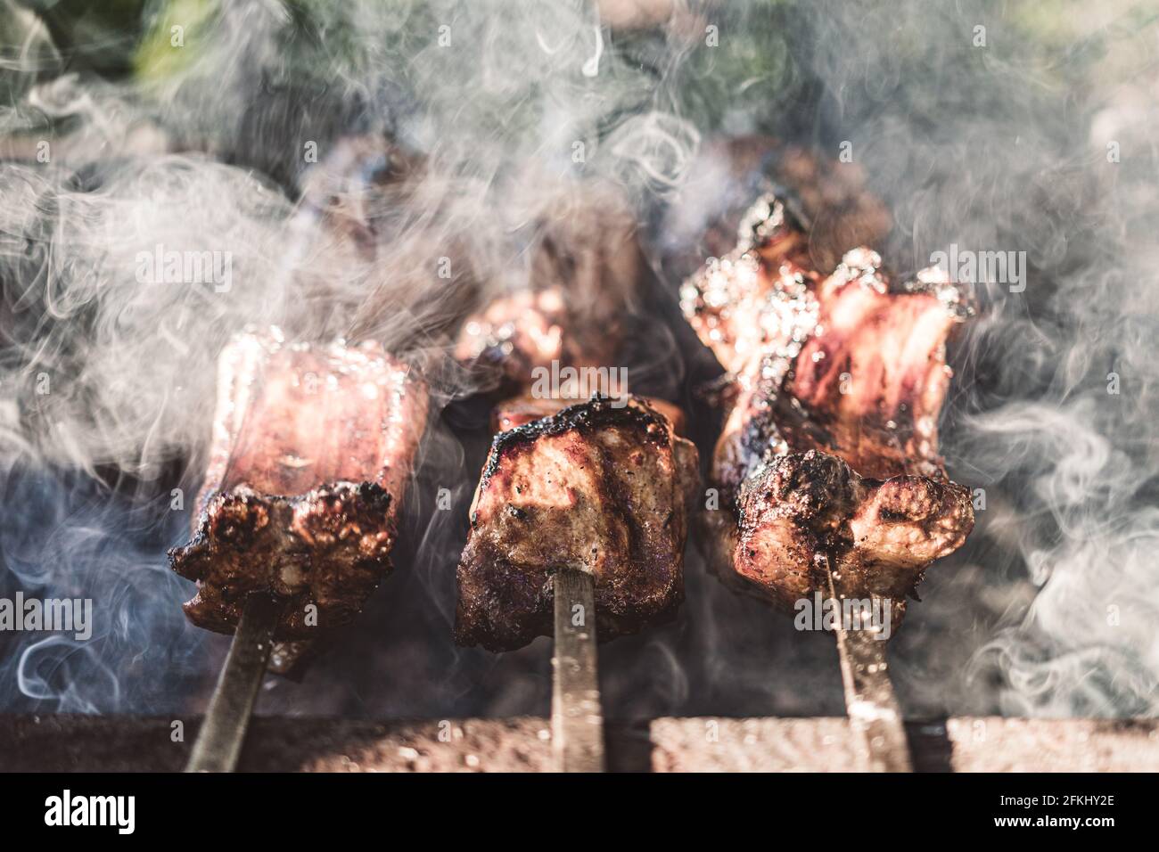 Carne alla griglia. Barbecue mattutino. Cucina barbecue sulla griglia con fumo. Cuocere la carne fresca marinata con cipolle. Barbecue marinato alla griglia Foto Stock