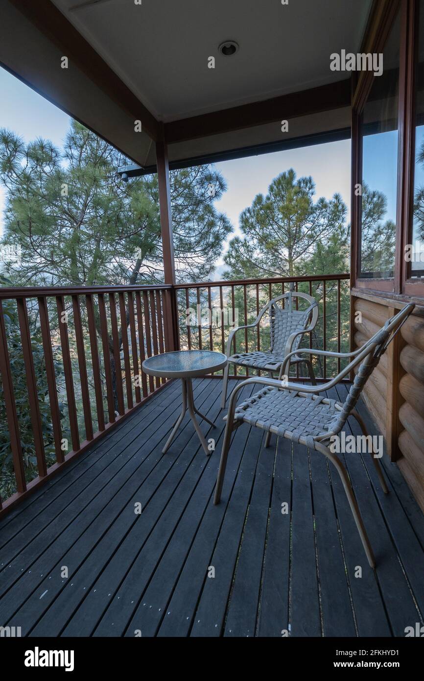 Una vista panoramica dal balcone con alberi tutto intorno e sedie tenute per il relax Foto Stock