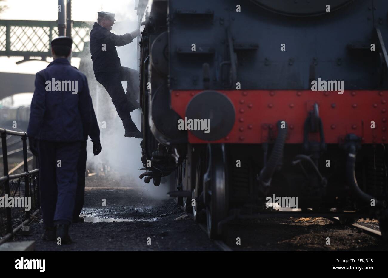 Un autista salta a bordo della locomotiva a vapore British Railways Standard Class 4MT 76017 nel cantiere alla stazione di Rotley prima del terzo giorno della Spring Steam Gala sulla Mid Hants Railway, nota anche come linea di Watercress, nell'Hampshire. Data immagine: Domenica 2 maggio 2021. Foto Stock