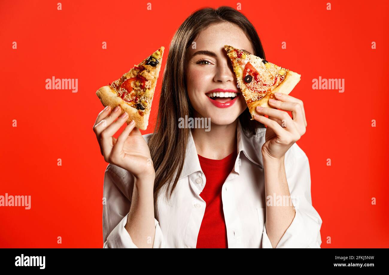 Happy woman tiene due fette di pizza, ridendo e sorridendo, come mangiare fastfood gustosa pizzeria da asporto, invitare gli amici per pranzo ordinare cibo Foto Stock