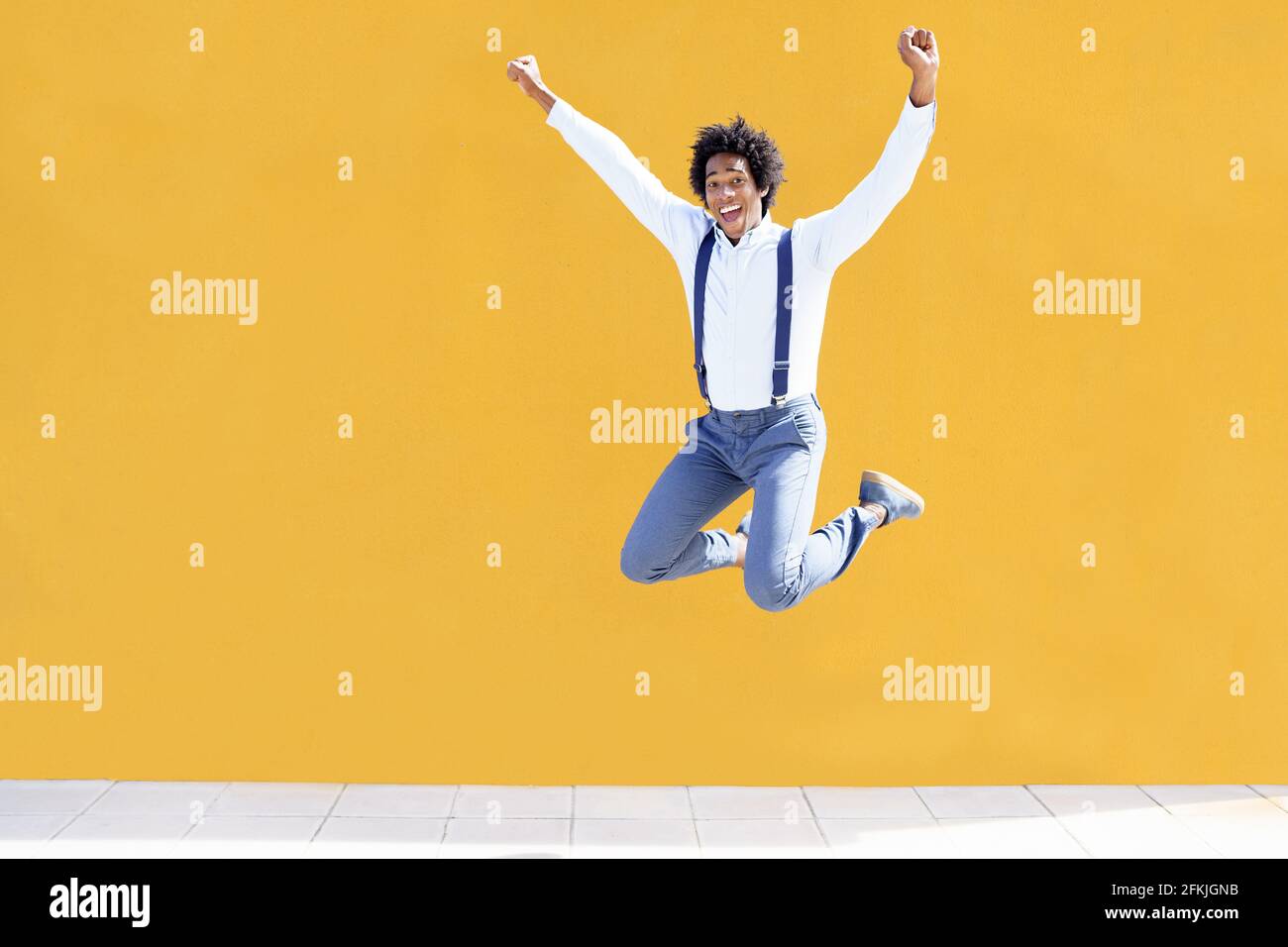 Uomo nero con capelli afro che salta su una città gialla sfondo Foto Stock
