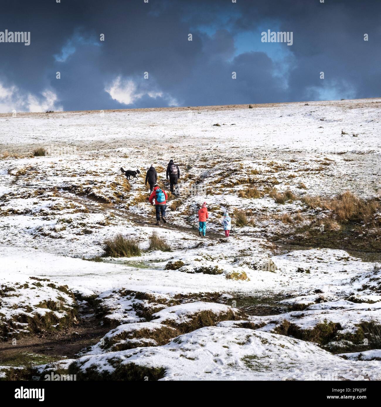 Una famiglia che si gode una passeggiata nella neve sul selvaggio e aspro Rough Tor su Bodmin Moor in Cornovaglia. Foto Stock