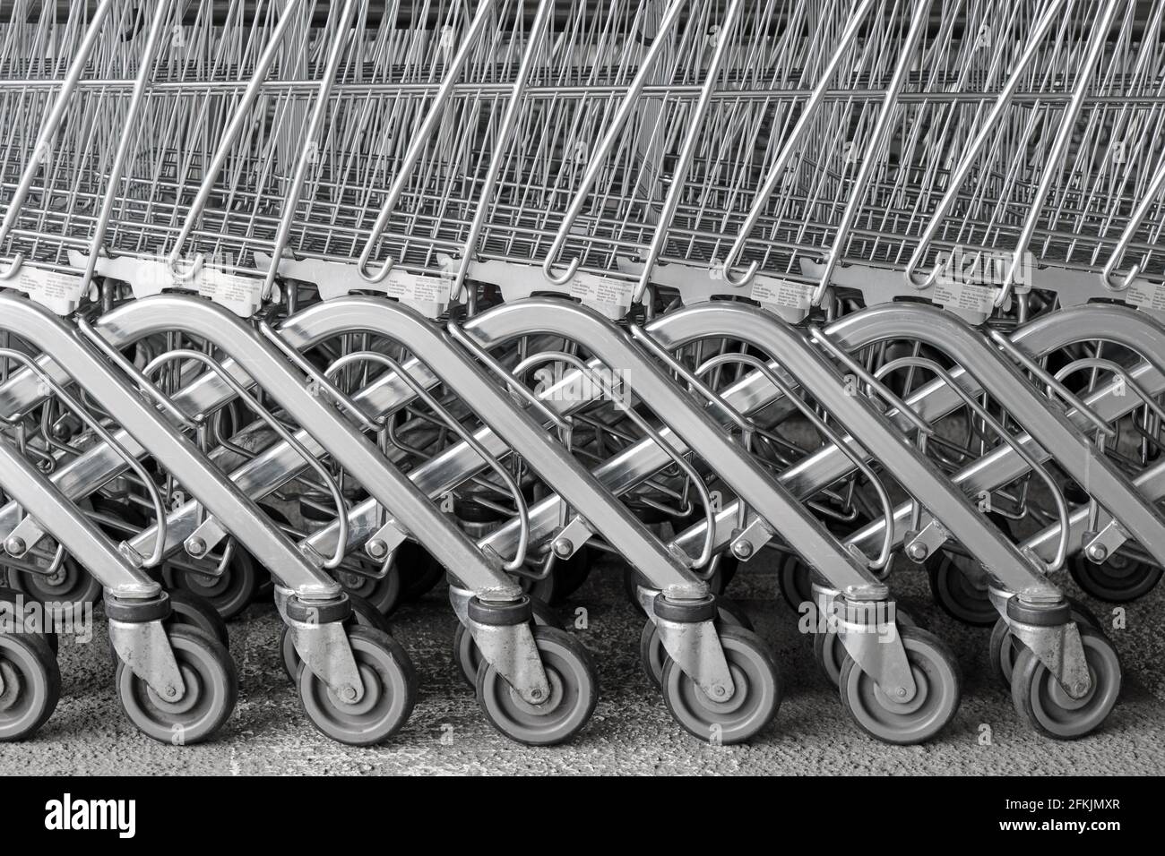 Fila di carrelli per carrelli per supermercati, fondo industriale in metallo bianco e nero Foto Stock