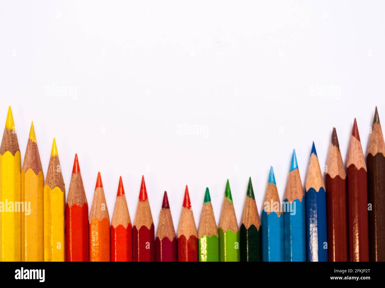 Sfondo bianco con una disposizione parallela di matite colorate con un campo di testo di grandi dimensioni Foto Stock