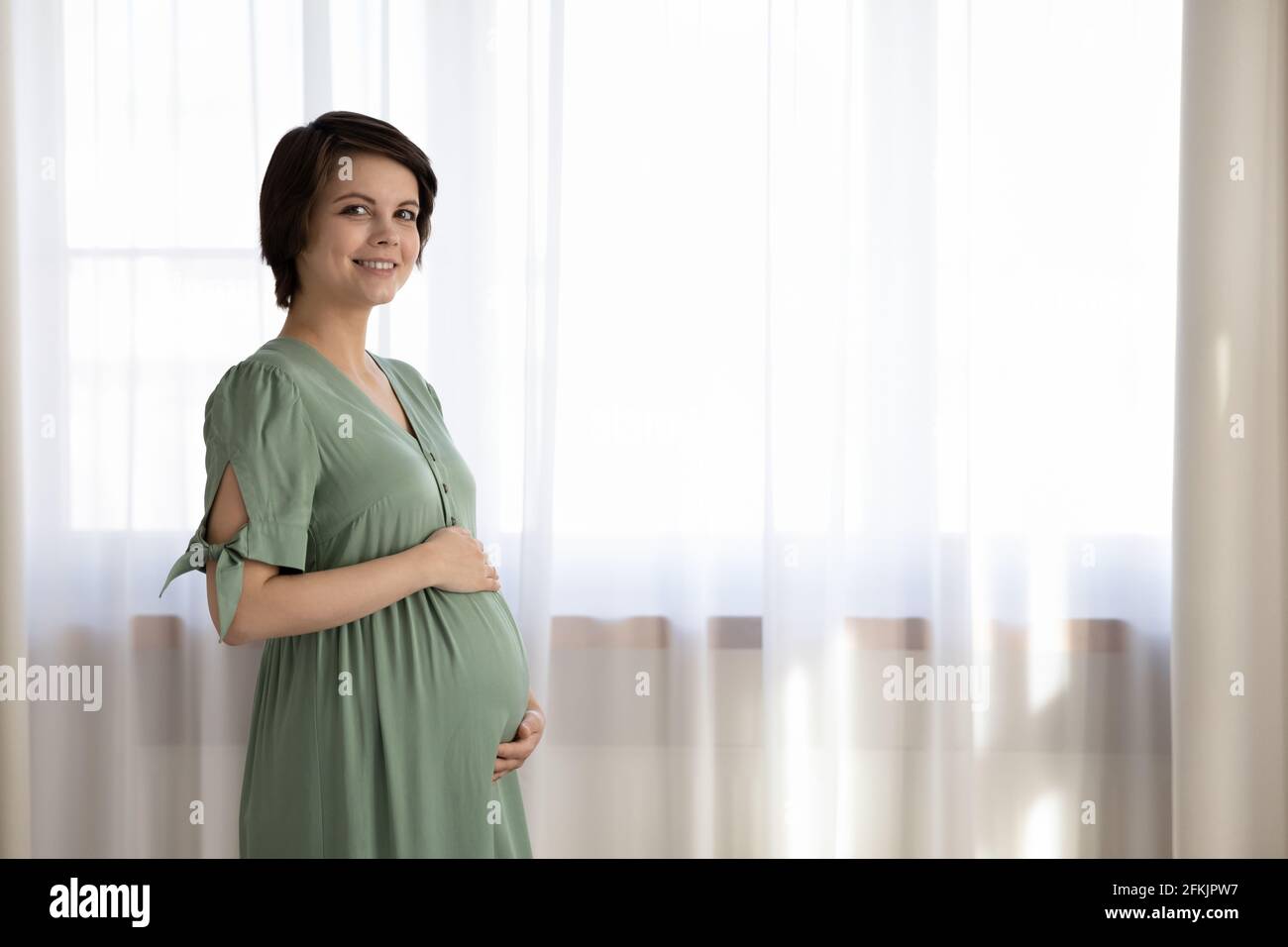 Ritratto di donna incinta sorridente carezza pancia Foto Stock