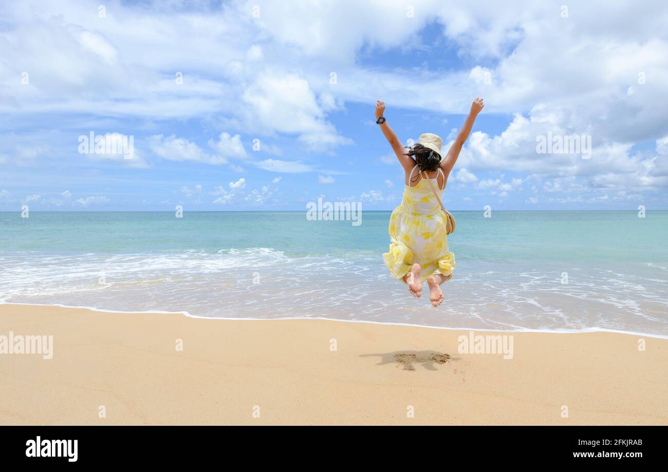 Eccitato felice ragazza turistica è saltando in spiaggia in vacanze estive, divertimento e libertà con nuovi concetti di viaggio normale Foto Stock