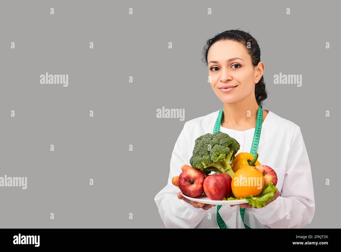 Dieta sana. Nutrizionista con frutta e verdura per la dieta in mani su sfondo grigio Foto Stock