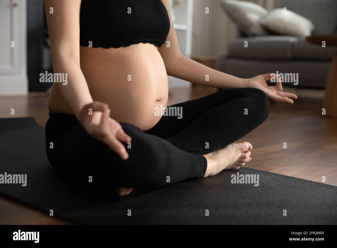 Primo piano di una donna incinta pratica yoga a casa Foto Stock