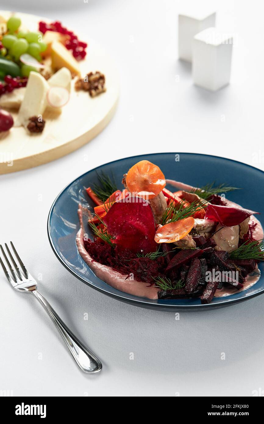 Insalata estiva di barbabietole con rucola, radicchio, formaggio morbido e noci su piatto condimento e spezie su piatto blu, spazio copia, vista dall'alto. Foto Stock